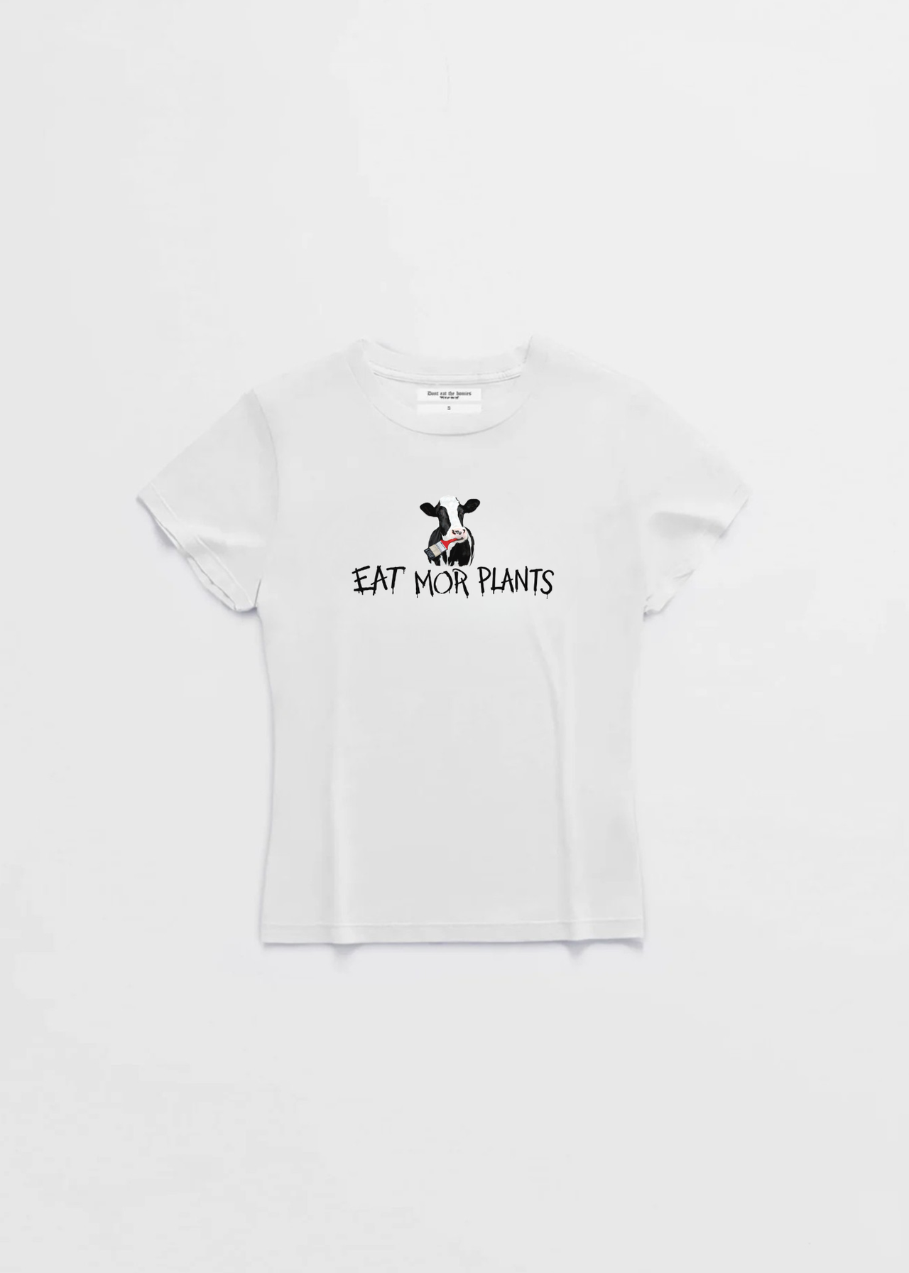Woman wearing a white t-shirt with 'Eat Mor Plants' on a beach